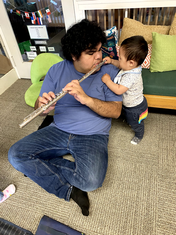 Teacher playing flute with baby watching